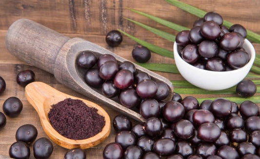 Acai berries and acai powder on a wooden surface, showcasing their rich purple color and health benefits.