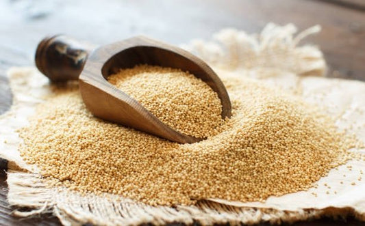 A wooden scoop filled with amaranth seeds on a rustic cloth, highlighting its nutritious benefits.