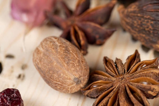 Close-up of anis seeds and star anise on a wooden surface, highlighting their unique colors and textures.