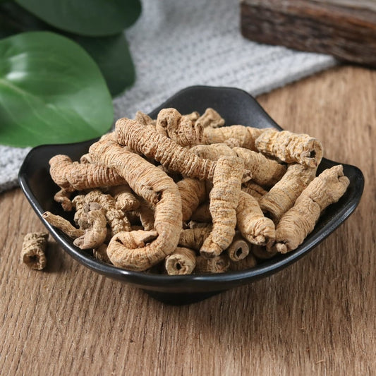 Ba Ji Tian herbal roots in a black bowl on a wooden surface, highlighting natural health benefits.
