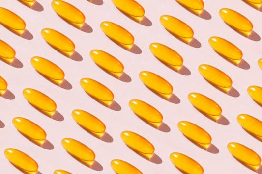 Rader av gula omega-3 kapslar på en ljus bakgrund, symboliserar hälsofördelar.