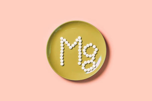 White tablets arranged to form 'Mg' on a green plate, symbolizing magnesium's importance in health.