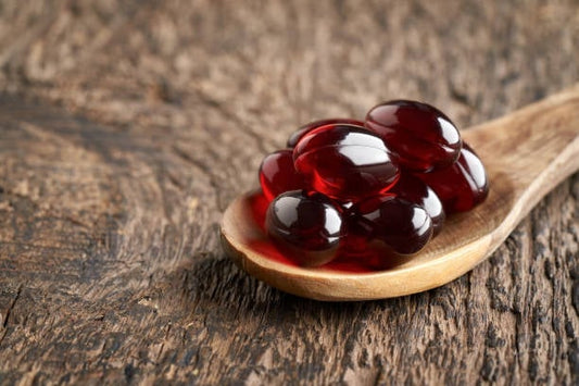Röda krilloljekapslar på en träsked, en naturlig källa till omega-3 fettsyror.