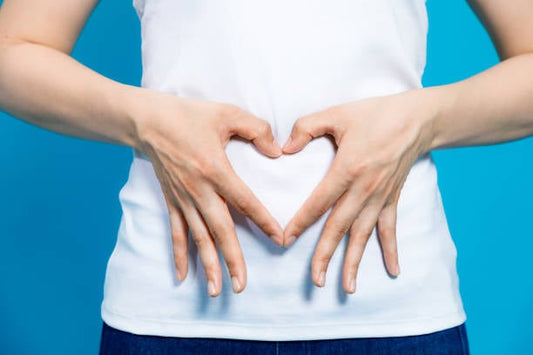 Person forming a heart shape with hands on their stomach, symbolizing gut health and well-being.