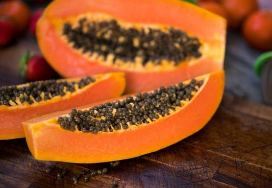 Nyutskarvad papaya med frön, en näringsrik frukt som gynnar hälsan, placerad på en träskiva.