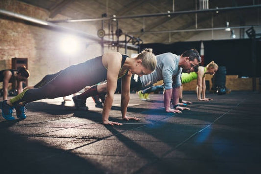 Group of people performing push-ups in a gym, focusing on strength training and fitness.