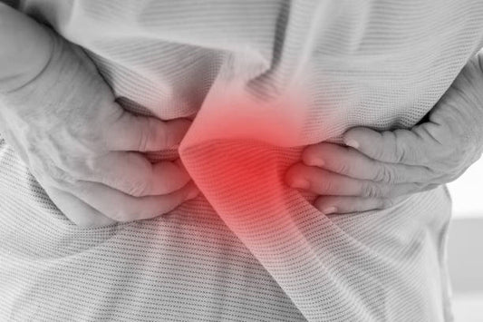 Elderly person holding lower back in pain, illustrating chronic back pain and discomfort.