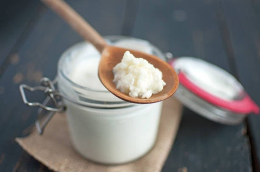 Kefir in a glass jar with a wooden spoon, showcasing its creamy texture and health benefits.