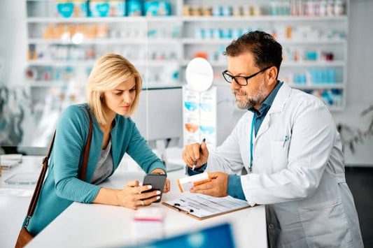 A pharmacist discussing vitamin combinations with a customer at a pharmacy.