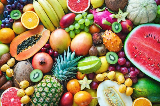 A colorful assortment of tropical and seasonal fruits including bananas, watermelon, and grapes.