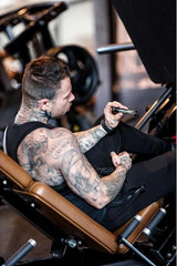 Man with tattoos holding BioTechUSA Magna Shot in the gym, focusing on fitness and wellness.