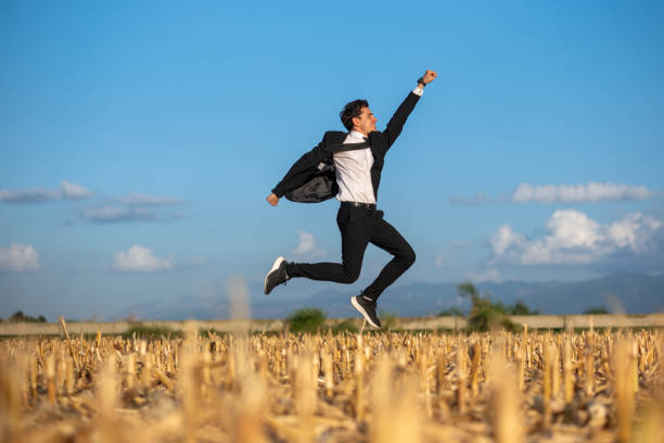 Joyful man in a suit jumping in a golden field, symbolizing success and celebration.