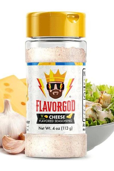 FlavorGod Cheese Flavored Seasoning bottle, vegan, lactose-free, with cheese, garlic, and salad in the background.