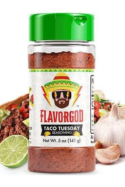 FlavorGod Taco Tuesday Seasoning bottle with vibrant label next to tacos and fresh ingredients.