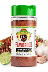 FlavorGod Taco Tuesday Seasoning bottle with vibrant label next to tacos and fresh ingredients.