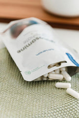 Nutriversum glucosamine sulfate capsules spilling from packaging onto a textured surface.