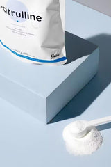 Nutriversum L-Citrulline unflavored powder on a blue surface with a scoop.