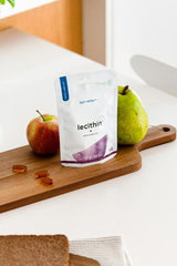Nutriversum Lecithin softgels on a wooden board with an apple and pear, promoting healthy living.