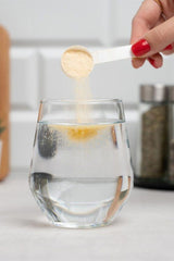 Pouring Nutriversum Multi Powder VITA into a glass of water for a refreshing drink.