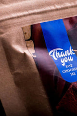 Close-up of a product package with a 'Thank you for choosing me' label on brown paper.