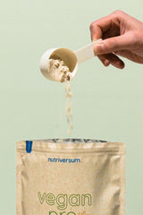Hand pouring Nutriversum Vegan Pro protein powder into a bag for muscle building and recovery.
