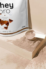 Nutriversum Whey PRO - PURE protein powder package with a scoop on a surface, showcasing chocolate flavor and premium quality.