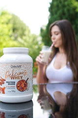 OstroVit Delicious WHEY protein shake with a woman enjoying a drink outdoors.