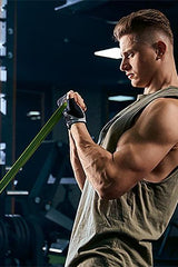 Muscular man using a green resistance band for strength training in a gym setting.