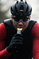 Cyclist in rain consuming Science in Sport GO Energy + Caffeine Gel during intense workout.