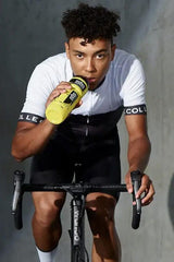 Athlete on a bike drinking Science in Sport Turbo+ Powder from a yellow bottle during training.