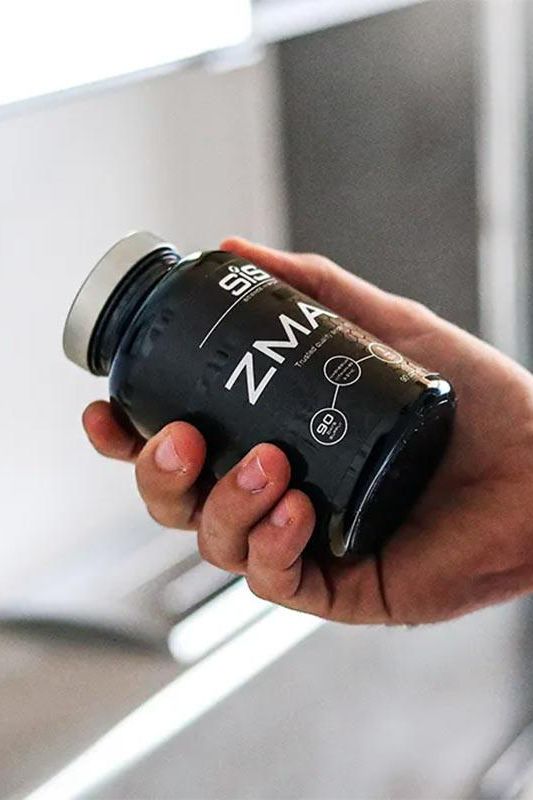 Hand holding Science in Sport ZMA supplement bottle, 90 capsules for strength and recovery. Hand holding Science in Sport ZMA supplement bottle, 90 capsules for strength and recovery.