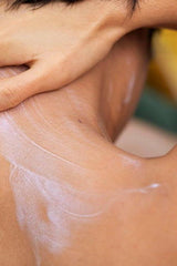Applying body butter to the back of the neck for hydration and skin nourishment.