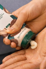 Applying The Body Shop vegan shea body lotion from a tube, demonstrating its creamy texture for moisturizing skin.