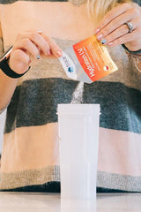 Person pouring Trace Minerals Hydration I.V. electrolyte powder into a shaker bottle.