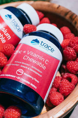 Trace Minerals Zinc + Vitamin C Chewable supplement in raspberry flavor surrounded by fresh raspberries.