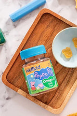 Wellkid Peppa Pig Omega-3 DHA gummies in a jar on a wooden tray with a blue plate.