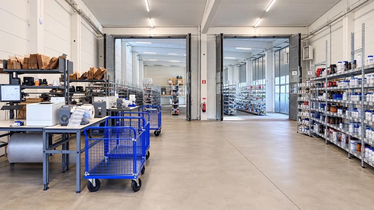 Pakkestationer, emballagematerialer og blå plukkevogne på lageret
