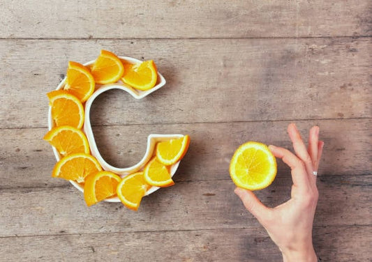 Sliced oranges arranged in the shape of the letter C with a hand holding a lemon slice.