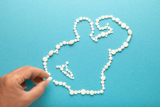 Hand arranging white pills into a figure on a blue background, symbolizing health and fitness.