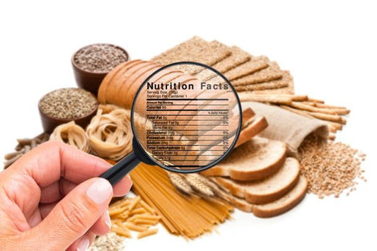 Hand holding a magnifying glass over nutritious grains and bread, highlighting nutrition facts for healthy eating.