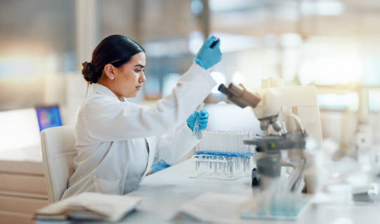 Kvinna i laboratorium utför experiment med provrör och mikroskop.