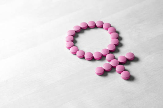 Pink pills arranged to form the female gender symbol, representing women's health and hormones.