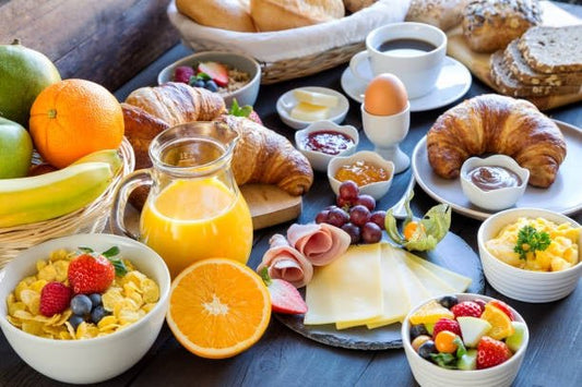 En överflöd av frukostalternativ inklusive croissanter, frukt, juice och kaffekoppar på ett bord.