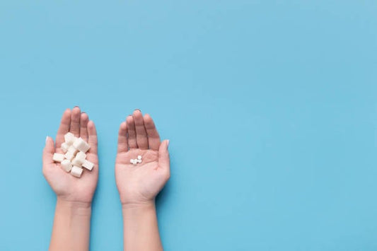 Two hands holding sugar cubes on one side and sugar substitutes on the other, illustrating sweetener choices.