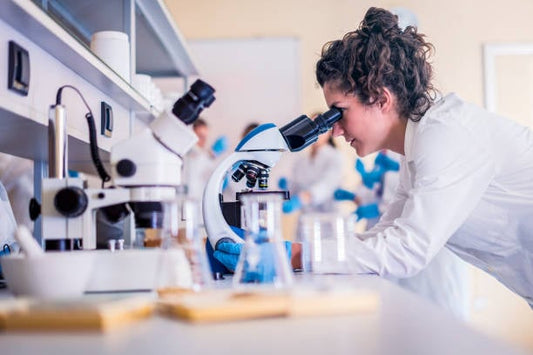 Scientist observing samples under a microscope in a modern laboratory setting.