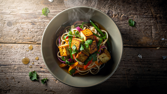Skål med färska nudlar toppade med grönsaker, tofu och örter