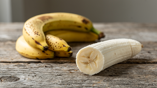 Mogna gula bananer på ett trabord, en uppskuren banan visar fruktkottet