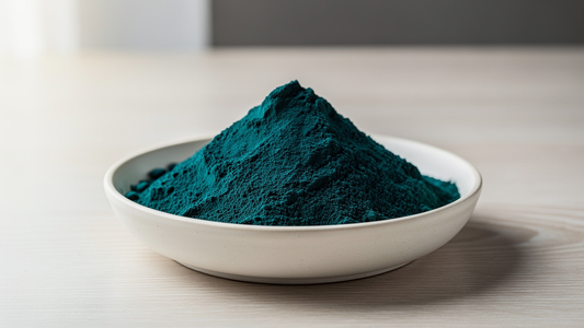 Skål med blågrönt spirulinapulver på ljust träbord