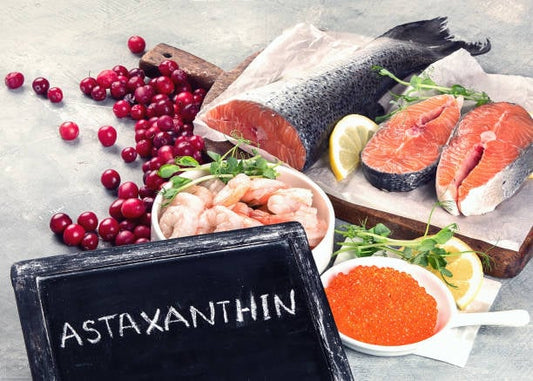 Astaxanthin ingredients including salmon, shrimp, lemon, and berries on a rustic table.