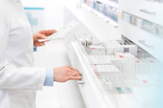 Pharmacist reviewing medication prescriptions in a modern pharmacy setting.